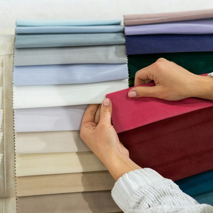 The woman chooses the fabric on the sofa. Textile industry background. Tissue catalog
